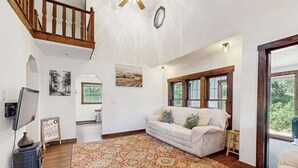 Uma sala de estar acolhedora com um sofá, um tapete, uma televisão e uma lareira.