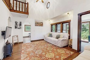 A cozy living room with a sofa, a rug, a television, and a fireplace. - Cozy Home in the trees, w/ large yard, fire pit, gas grill, & WIFI (Friendship)