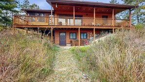 Een houten chalet met twee verdiepingen, een balkon, een voordeur en een schoorsteen.