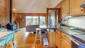 Een houten blokhut van binnen met een keuken, een eethoek en een trap naar een balkon.