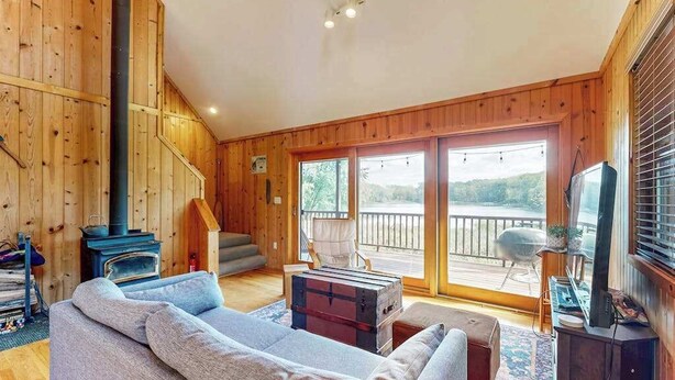 Een houten interieur met een bank, een open haard, een televisie en een balkon met uitzicht.