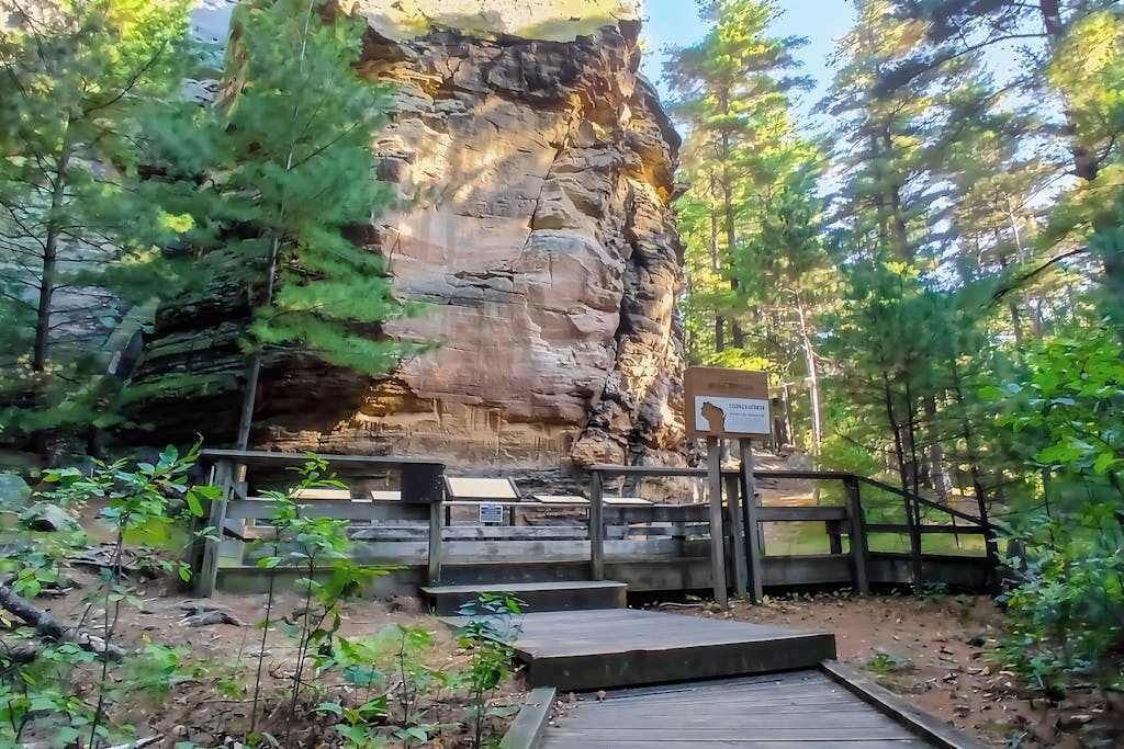 A natural rock formation with a wooden viewing platform and a sign.