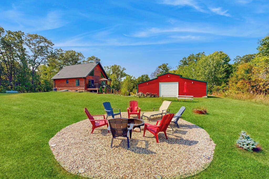 A red barn with a white garage door, surrounded by a grassy field and trees.