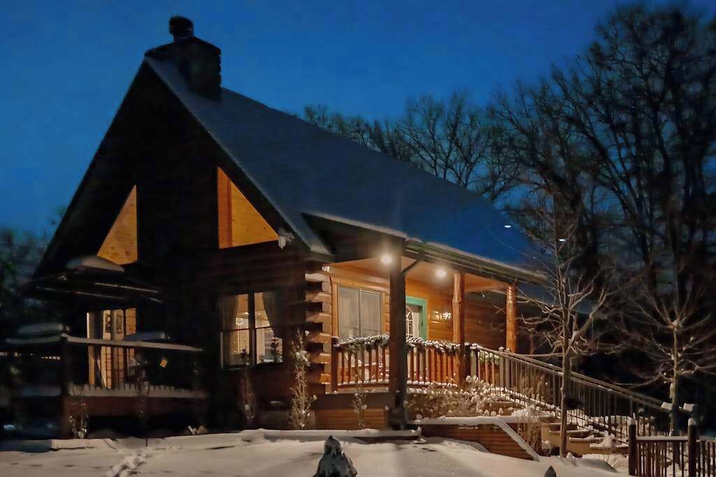 Een blokhut met veranda, houten gevel en sneeuw op de grond.