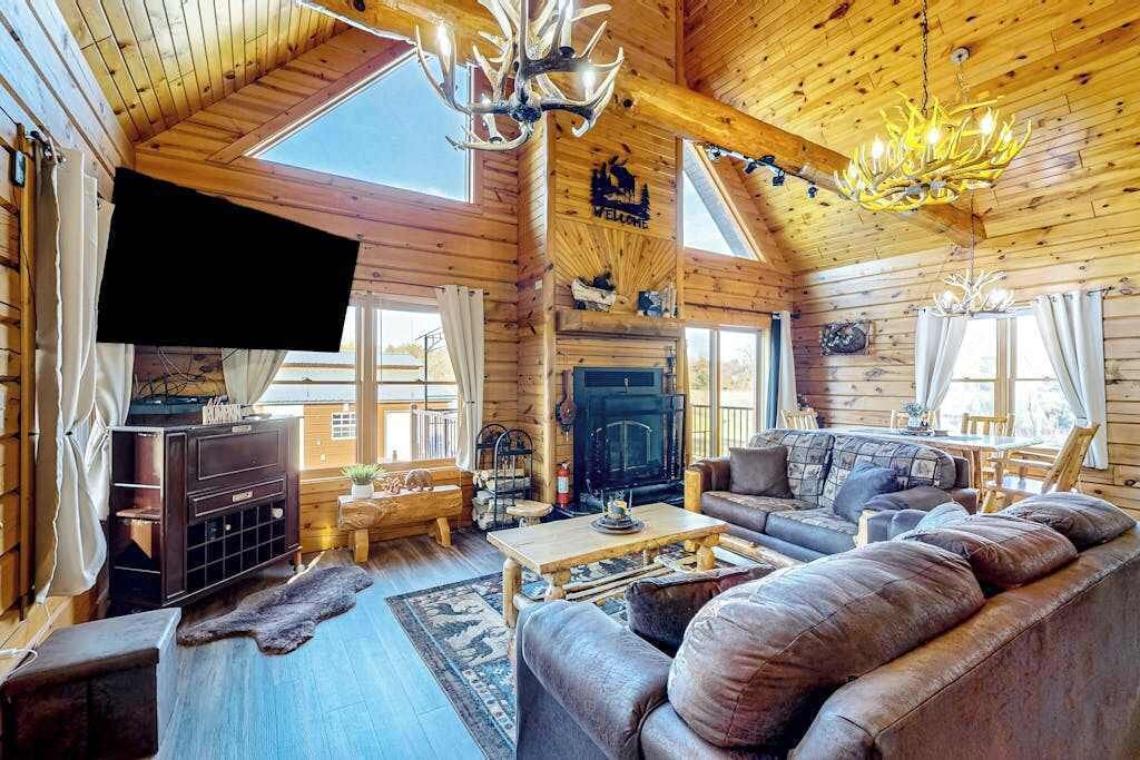 A log cabin interior with a fireplace, wooden furniture, and a television.