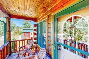 Eine Holzhütte mit Veranda, zwei Stühlen und einem Fenster mit dekorativem Rahmen.
