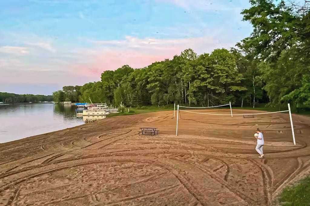 A volleyball court with a net, a bench, and a person playing.