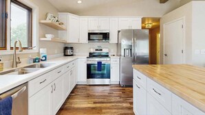 Eine moderne Küche mit weißen Schränken, Edelstahlgeräten und einer Holz Arbeitsplatte.