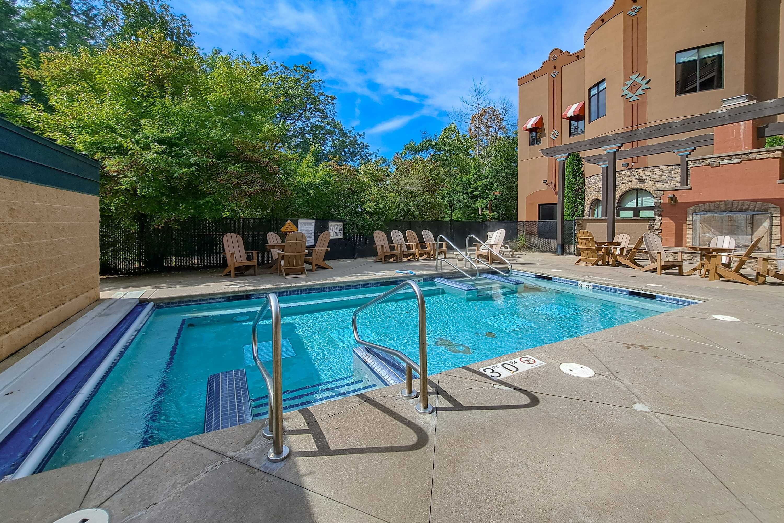 A swimming pool with lounge chairs and a building with a stone facade.