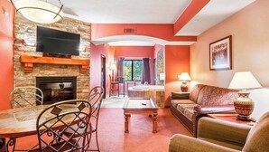 Ein Wohnzimmer mit Kamin aus Stein, einem darüber montierten Fernseher, einem Billardtisch und einem Sofa.