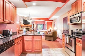 A kitchen with a central island, a dining area with a table and chairs, and a living room with a sofa and a fireplace. - Spacious Condo & Studio with Jetted Tub & Balcony (Wisconsin Dells)