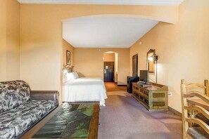 A hotel room with a bed, a sofa, a desk, and a mirror.