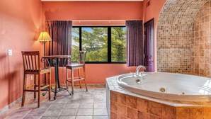 Une salle de bain avec une grande baignoire, une fenêtre avec des rideaux et une table avec des chaises.