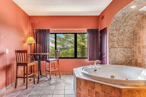 A bathroom with a large bathtub, a window with curtains, and a table with chairs. - Riverside Golf Resort Condo with Full Kitchen (Wisconsin Dells)