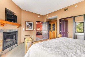 A hotel room with a fireplace, a television, a bed, a door, and a window. - Riverside Golf Resort Condo with Full Kitchen (Wisconsin Dells)