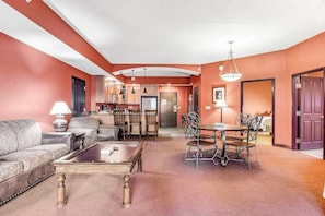 A living room with a sofa, coffee table, and dining area with chairs and a table. - Riverside resort condo with on-site golf, dining (Wisconsin Dells)