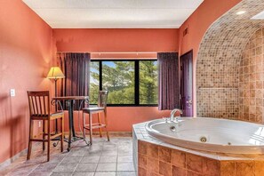 A bathroom with a large bathtub, a window with curtains, and a table with chairs. - Riverside resort condo with on-site golf, dining (Wisconsin Dells)