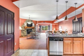 A kitchen with a stone fireplace, wooden cabinets, and pendant lighting. - Riverside resort condo with on-site golf, dining (Wisconsin Dells)
