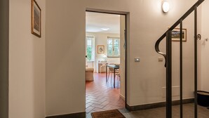 Ein Flur, der in einen Essbereich mit Tisch und Stühlen führt, eine Treppe mit Handlauf sowie ein gerahmtes Bild an der Wand.