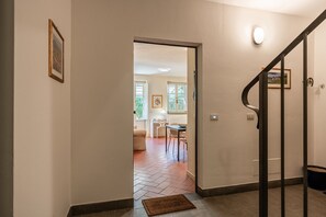 A hallway leading to a dining area with a table and chairs, a staircase with a handrail, and a framed picture on the wall. - Casa Elisa - Lucca with Private Garden and Garage (Lucca)