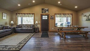 A spacious living room with a sofa, a dining table, and a bench. - Contemporary dog-friendly cabins with hot tub, fireplaces, patios, & game room (Conover)