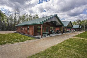A lodge with a covered patio, wooden exterior, and a gravel driveway. - Modern dog-friendly cabin with hot tub, gas fireplace, patio, grill, & washer/dr (Conover)