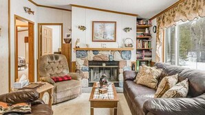 Ein gemütliches Wohnzimmer mit Kamin, Ledersofas, einer Bücherwand und Blick ins Grüne.
