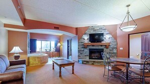 Ein Wohnzimmer mit Kamin, einem Essbereich mit Metallstühlen, einem Sofa und einer Lampe.