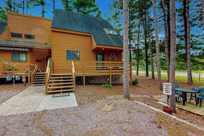 A log cabin with a porch, outdoor seating, and a parking sign.