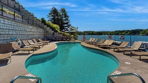 A pool with lounge chairs, a stone wall, and a view of the surrounding landscape. - Ultimate relaxation awaits at this luxe lakefront Delton Grand studio (Wisconsin Dells)