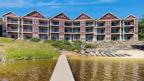 A multi-story hotel with balconies, a dock leading to a body of water, and a rocky shoreline. - Ultimate relaxation awaits at this luxe lakefront Delton Grand studio (Wisconsin Dells)
