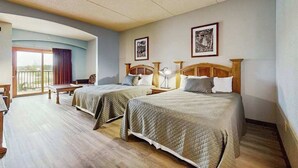 Habitación de hotel con dos camas, un escritorio, una silla y un balcón.