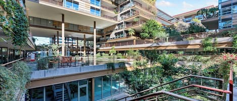 A multi-story building with balconies, outdoor seating, and a central courtyard with a pool.