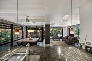 Eine moderne Küche mit Granit-Arbeitsplatten, einem Essbereich mit Holztisch und einer Sitzecke mit Sofa und Sesseln.