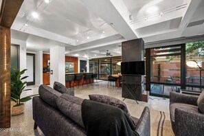 Ein modernes Wohnzimmer mit einer Couch, Sesseln und einer Essecke mit Fernseher und Bar.