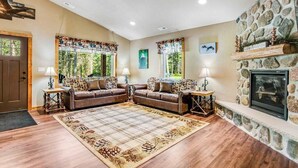 A living room with a fireplace, two sofas, a rug, and a stone wall.