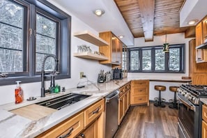 A modern kitchen with wooden cabinets, a built-in oven, and a large window.