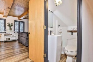 Un baño moderno con inodoro, lavamanos y espejo.