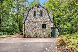 Un edificio de piedra con techo a dos aguas, dos ventanas y una puerta verde.
