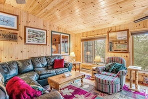 Un interior de madera con sofá de cuero, sillón a rayas y alfombra acolchada.