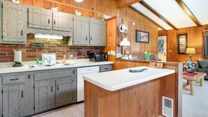 A kitchen with wooden cabinets, a microwave, and a dining area with a table and chairs. - Lakefront Home with a Private Dock, Deck, Fireplace, Spacious Yard, & Playset (Eagle River)