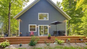 A two-story house with a covered porch, a grill, and a red chair. - Lakefront home with, dock, kayaks, paddle boards, fire pit & more (Conover)