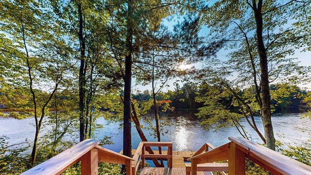 A wooden deck leading to a lake surrounded by trees. - Brand-new riverfront cabin with a open layout, gas grill, and W/D - dog-friendly (Tomahawk)