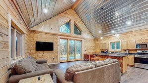 A log cabin interior with a living area, kitchen, and dining space. - Brand-new riverfront cabin with a open layout, gas grill, and W/D - dog-friendly (Tomahawk)