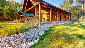 A log cabin with a covered porch, a staircase, and a gravel pathway. - Brand-new riverfront cabin with a open layout, gas grill, and W/D - dog-friendly (Tomahawk)