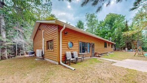 Eine Holzhütte mit Veranda, Grill und Gartenmöbeln.