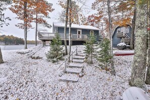 Eine Holzhütte mit einer Terrasse, umgeben von Bäumen und einer verschneiten Landschaft.