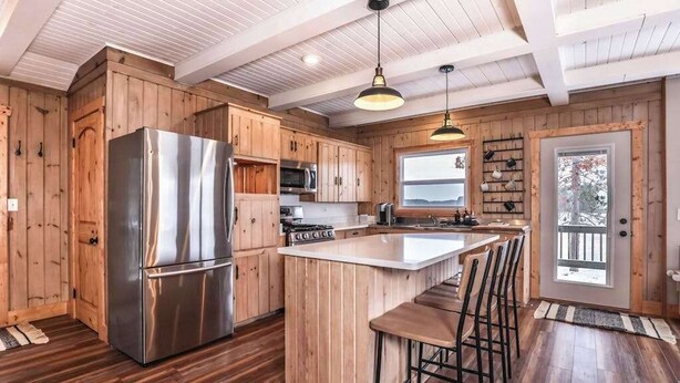 Una cocina moderna con armarios de madera, electrodomésticos de acero inoxidable y una isla central con taburetes.