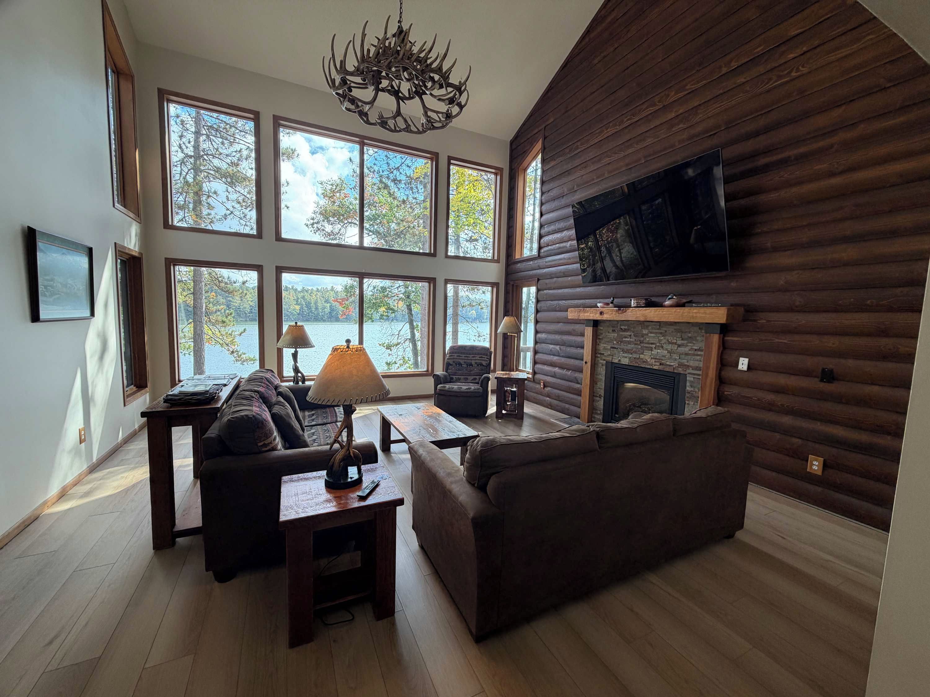 Una sala de estar amplia con chimenea, ventanas grandes y un televisor montado en la pared.
