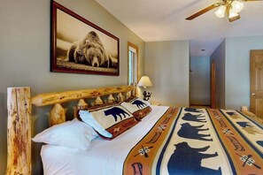 Una habitación con una cama, un ventilador de techo, un cuadro en la pared y una puerta.